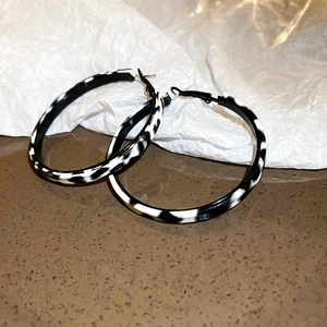 Macro shot of large black and white leopard print resin hoop earrings on a textured desk
