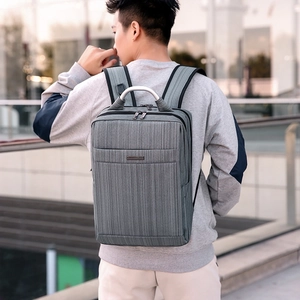 Man carrying a grey oxford business backpack with striped texture and metal handle outdoors