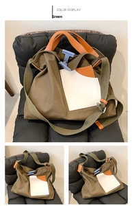 Detail view of large green canvas bucket bag with orange leather handles and blue buckle