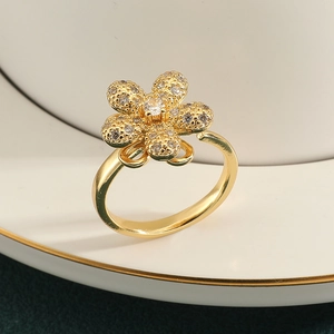 Macro detail of gold flower ring featuring central diamond and paved petals on dish
