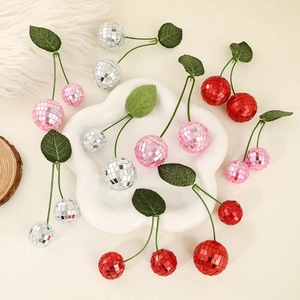 Disco ball cherry ornaments in red, pink, and silver with green leaves on a white tray