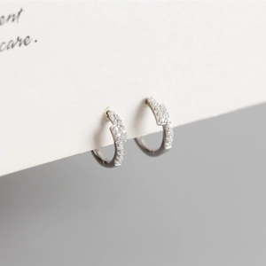 Detailed macro view of S925 silver huggie earrings with micro-set cubic zirconia stones