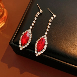 Close-up of red gemstone tassel earrings with diamond accents on a black jewelry box