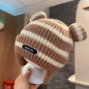 Detailed view of striped knit baby hat featuring ear flaps and cute pom-pom ears