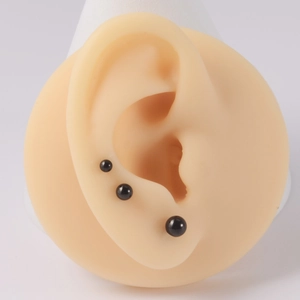 Ensemble de trois boucles d'oreilles sphériques noires de tailles variées sur modèle