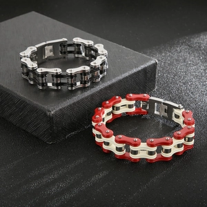 Detail of silver-black and red-white bicycle chain bracelets on textured surface