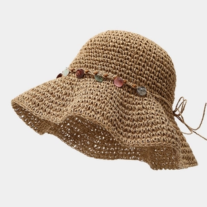 Détail d'un chapeau de paille tissé avec des paillettes en coquillage et un ruban délicat
