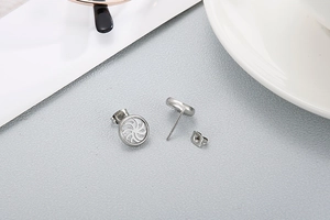 Macro detail of round stainless steel stud earrings with white swirl enamel inlay and backings