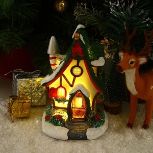 Close-up of glowing resin Christmas house with warm LED lights and glittery snow details