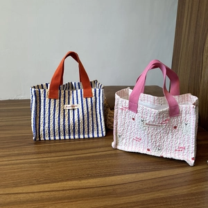 Dettaglio di borse tote a righe in tessuto goffrato con manici arancioni e rosa