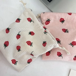 Macro detail of strawberry print corduroy drawstring bags in beige and pink colors