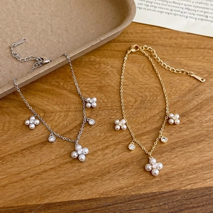 Detailed macro view of gold and silver flower bracelets with pearls and zircons on wood