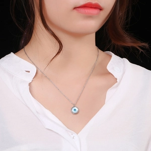 Silver evil eye necklace with blue and white enamel pendant shown on model's neck