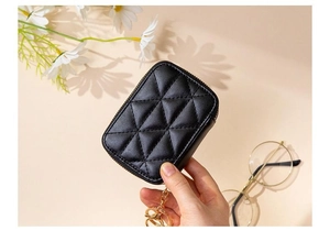 Quilted black leather makeup bag detail with golden zipper and keychain held by hand