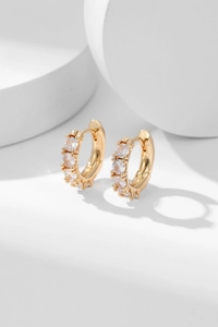 Macro shot of gold-plated hoop earrings with five sparkling clear cubic zirconia stones
