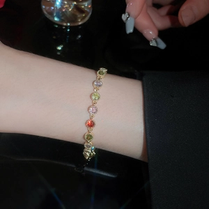 Detail of colorful round zircon gold plated bracelet worn on wrist in soft lighting