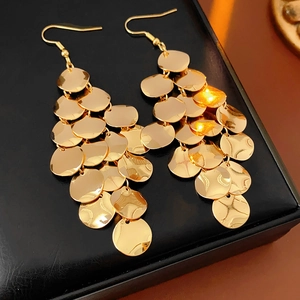 Macro shot of gold layered disc drop earrings on black leather display case