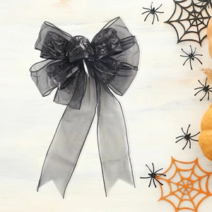Black lace Halloween bow decoration with spider webs and pumpkin on wood background