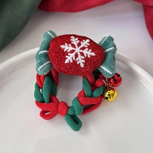 Détail d'un élastique tressé rouge et vert avec broderie flocon et cloches dorées