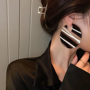 Close-up of stylish large round acrylic earrings with black and white stripes on a model