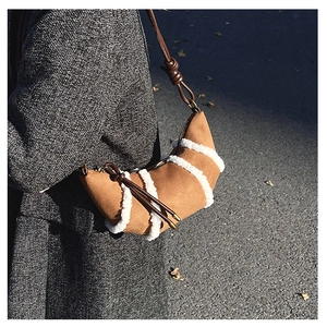 Detail der karamellfarbenen Croissant-Tasche mit Lammfellbesatz und geknotetem Riemen