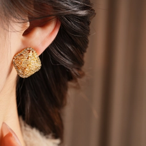 Close-up of elegant square zircon earrings in gold finish worn by a model