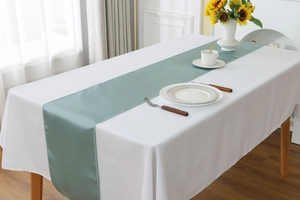 Detail view of light green satin table runner with a smooth reflective silk texture