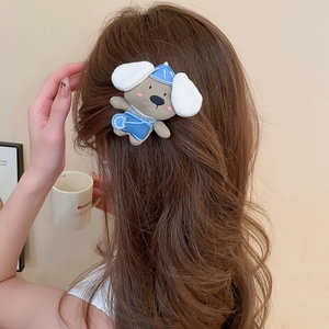 Close-up of a plush puppy hair clip with denim outfit worn on long wavy brown hair