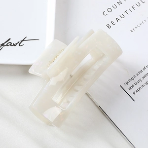 Detail of 10cm cream acetate hair claw clip showing marble texture and golden spring
