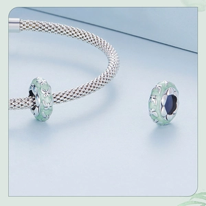 Macro view of silver mesh bracelet with two light green enamel butterfly pendants