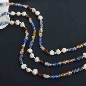 Detail showing irregular white pearls with blue lapis and tiger eye stone beads on a necklace