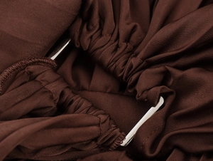Detail of chocolate brown pleated fabric with a rectangular silver metal buckle
