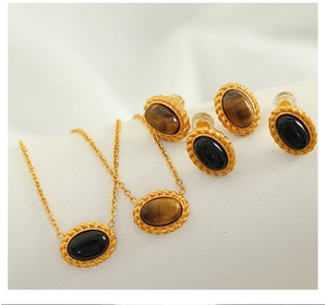 Detail of gold braided necklace and earrings set with oval tiger eye and black stones