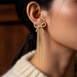 Detail of 18k gold plated bow earrings with long tassels and sparkling rhinestones