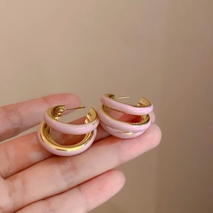 Dettaglio di orecchini a C rosa e oro che mostrano il metallo lucido e il design multistrato