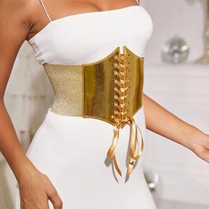 Detail of a golden lace-up cinch waist belt styled on a white dress for women