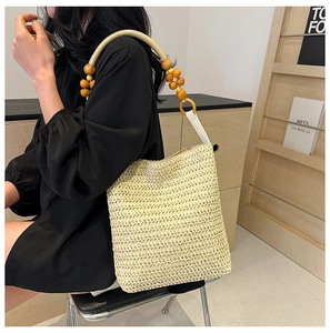 Detail of hand-woven straw tote bag with unique wooden beaded handle for summer style