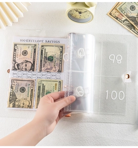 Detail showing hand inserting money into 100 day savings challenge envelope pockets