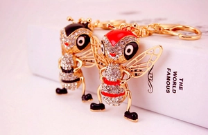 Detailed close-up of bee keychains with crystals and enamel on a decorative book