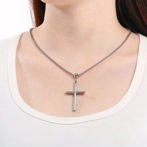 Close-up of minimalist silver stainless steel cross pendant necklace on male model