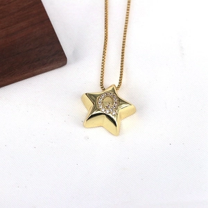 Detail shot of a golden star pendant with a zircon-inlaid letter Q on a snake chain