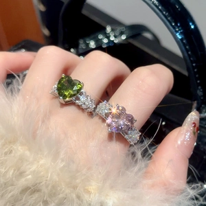 Detail of heart-shaped zircon rings in olive green and purple with diamond accents