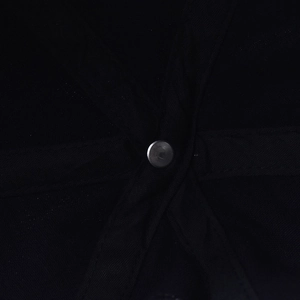 Macro shot of the six-panel stitching and metal top button on a black washed denim cap