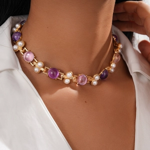 Close-up of vintage gold necklace with white pearls and colorful resin gemstones