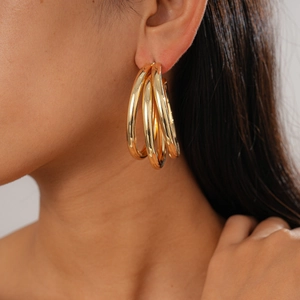 Close-up of model wearing gold triple-interlocking hoop earrings with geometric layers