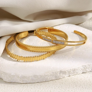 Three-piece 18K gold plated bangle set with zircons on white stone display