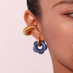 Detail of floral earring with resin petals and golden spiral cuff on model ear