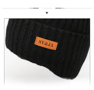 Gedetailleerde close-up van een zwarte gebreide muts met een leren patch en nette stiksels