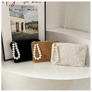 Detailweergave van pluche handtassen in drie kleuren met elegante parelhandvaten