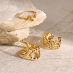 Three minimalist gold stainless steel rings with irregular and twisted designs on natural stone